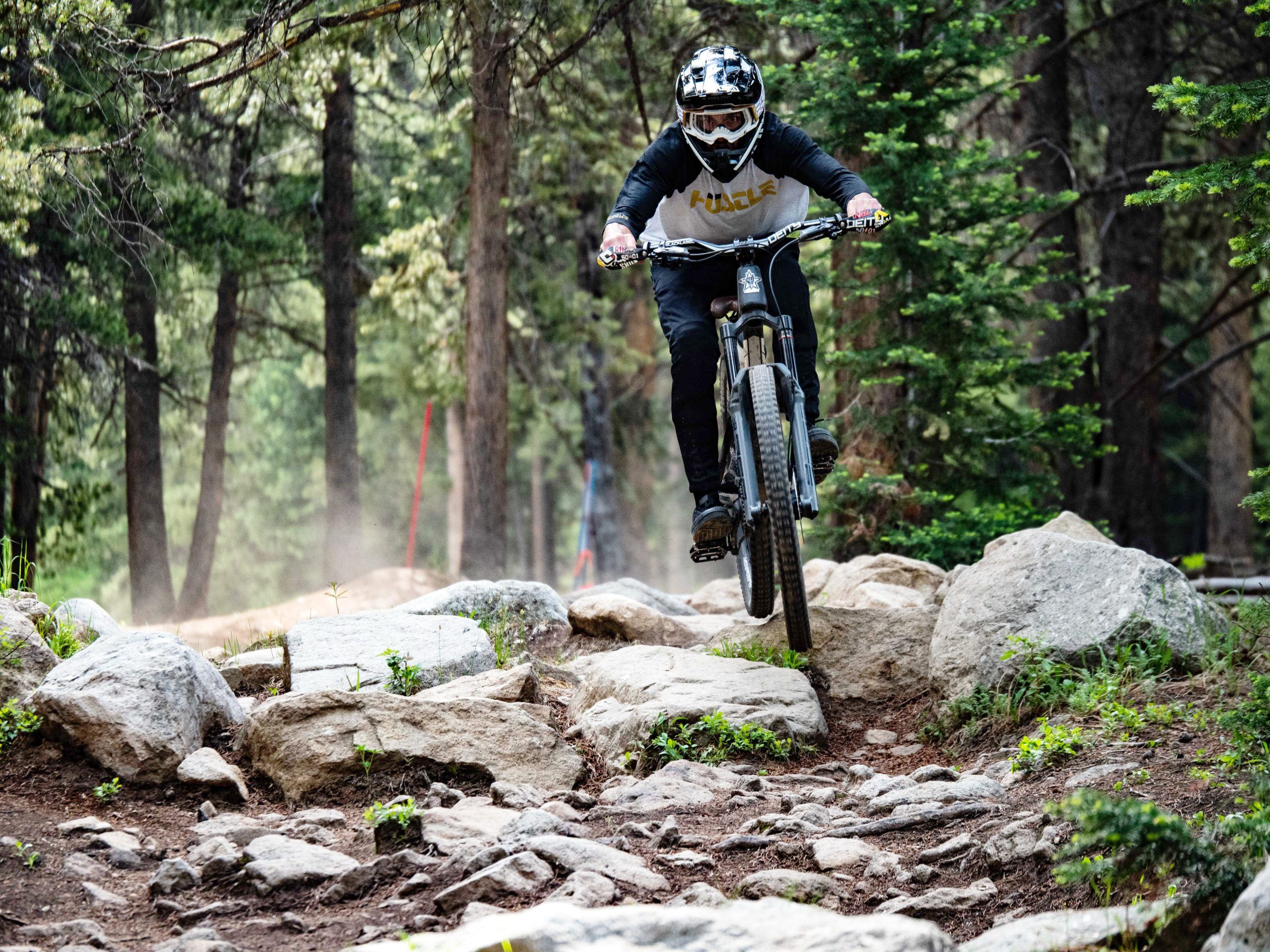 A mountain biker in a full-face helmet rides through a rock garden on the Crested Butte Mountain Bike Park Trails.