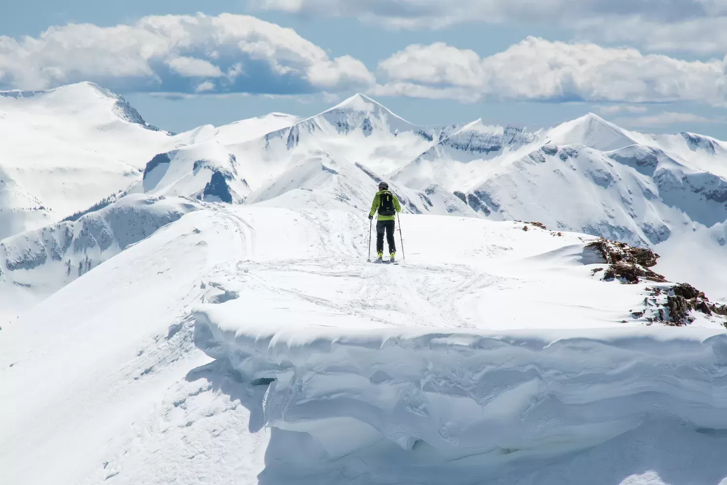 a skier faces snowy mountain peaks on top of a snowy ridge