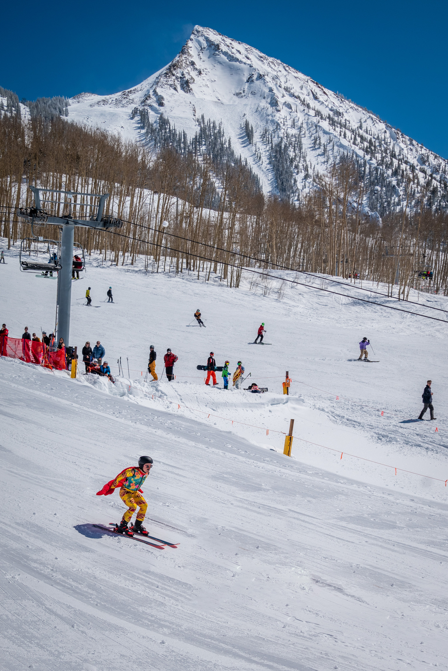 A person skiing down a hill with a mountain peak in the background. Crested Butte pond skim 