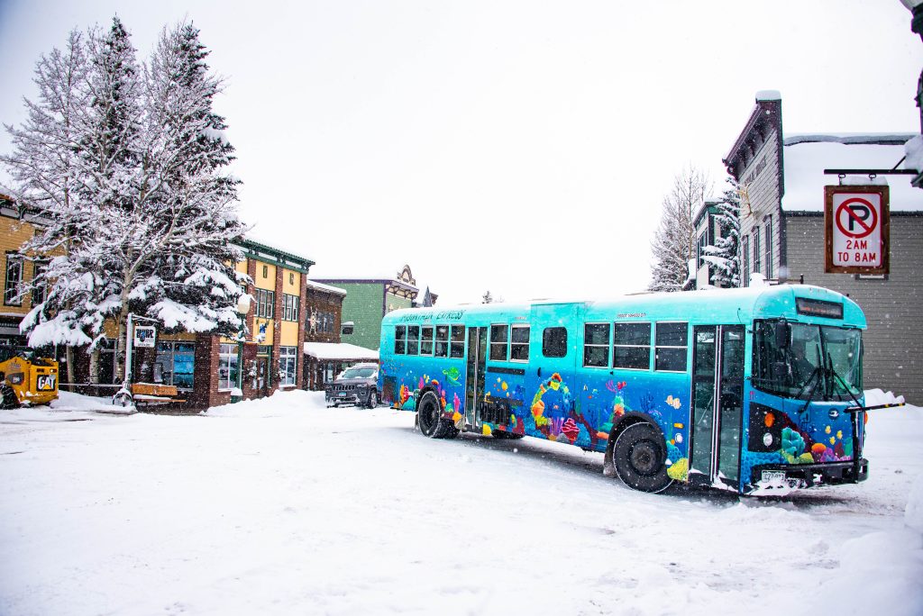 A Mountain Express town shuttle bus in Crested Butte, Colorado drives through downtown Crested Butte in the snow.