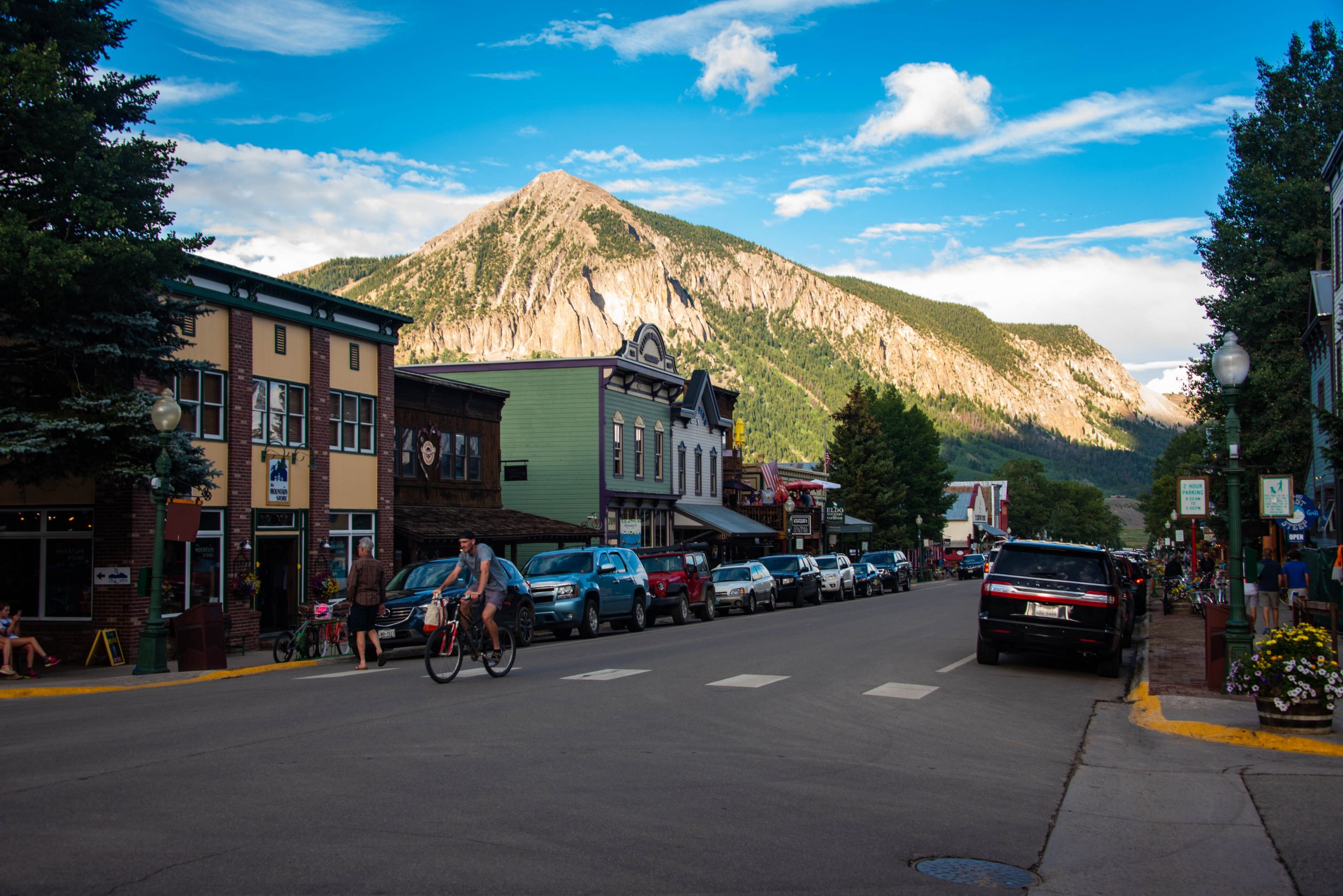 A view of downtown Crested Butte, Colorado with some shops, restaurants, and bars under mountain view. Someone is biking down the road.