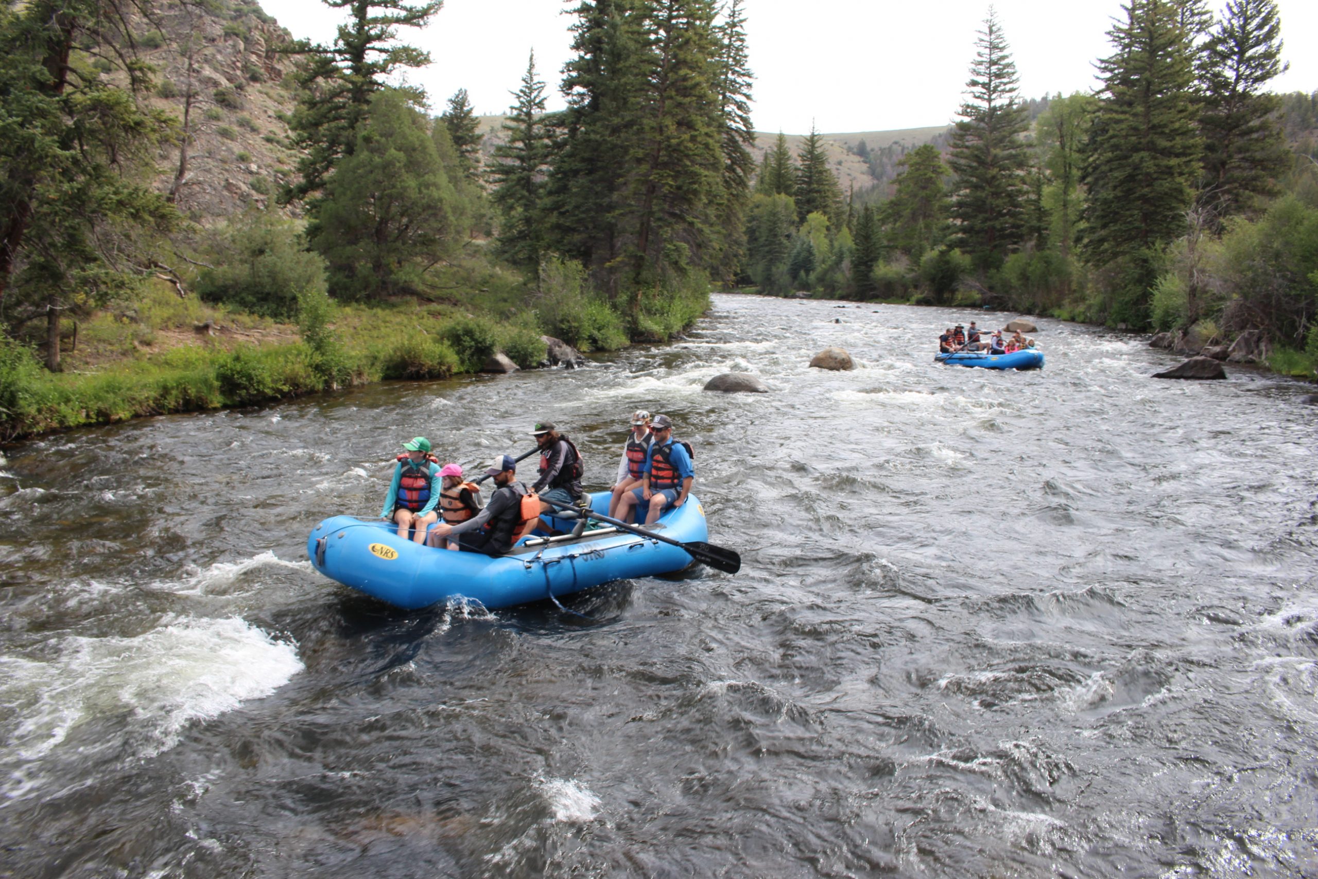Gunnison Valley river rafting two blue rafts are rowed down a river.