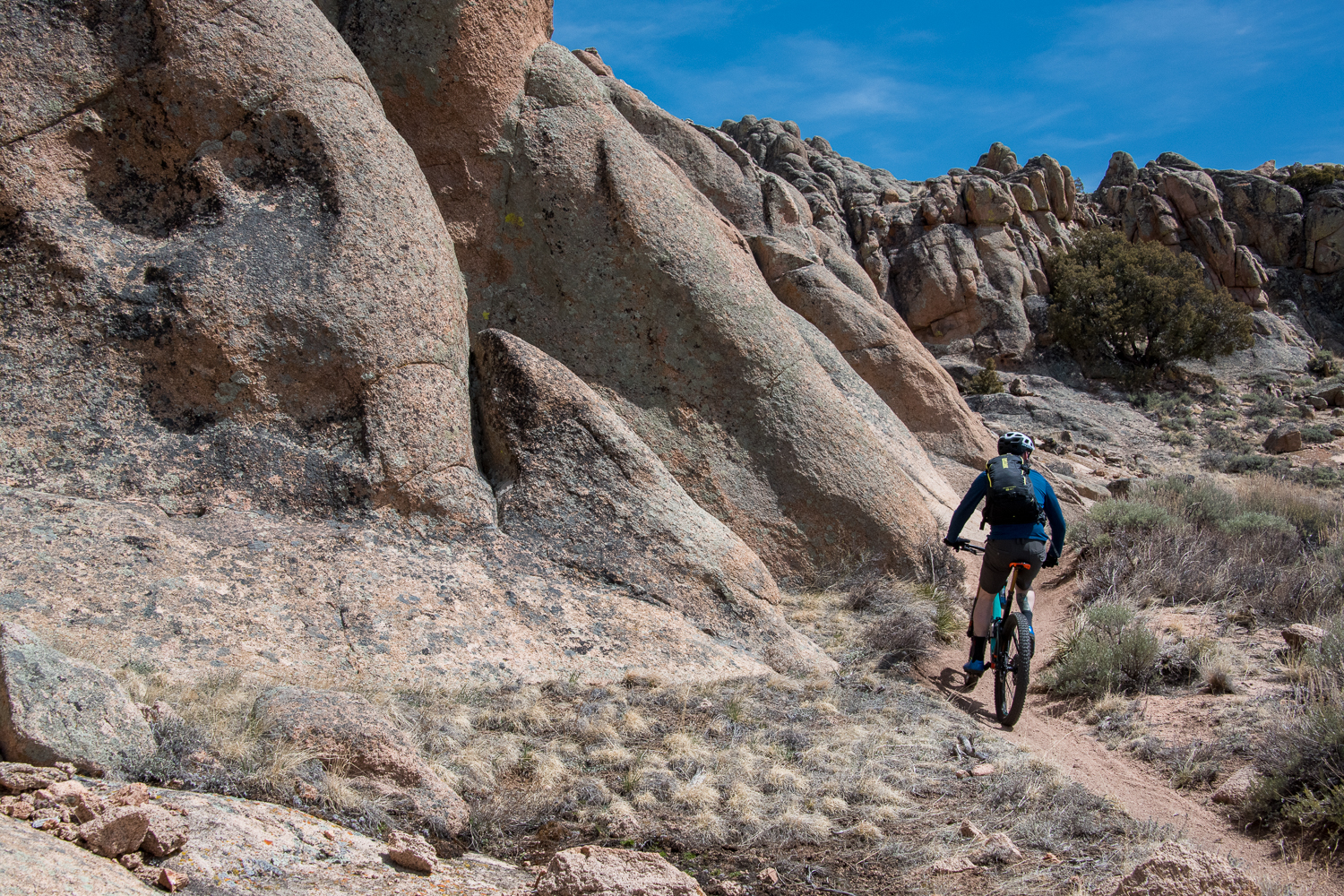 A person riding a mountain bike on a singletrack trail next to rock formations that are characteristic of MTB at Hartman Rocks 