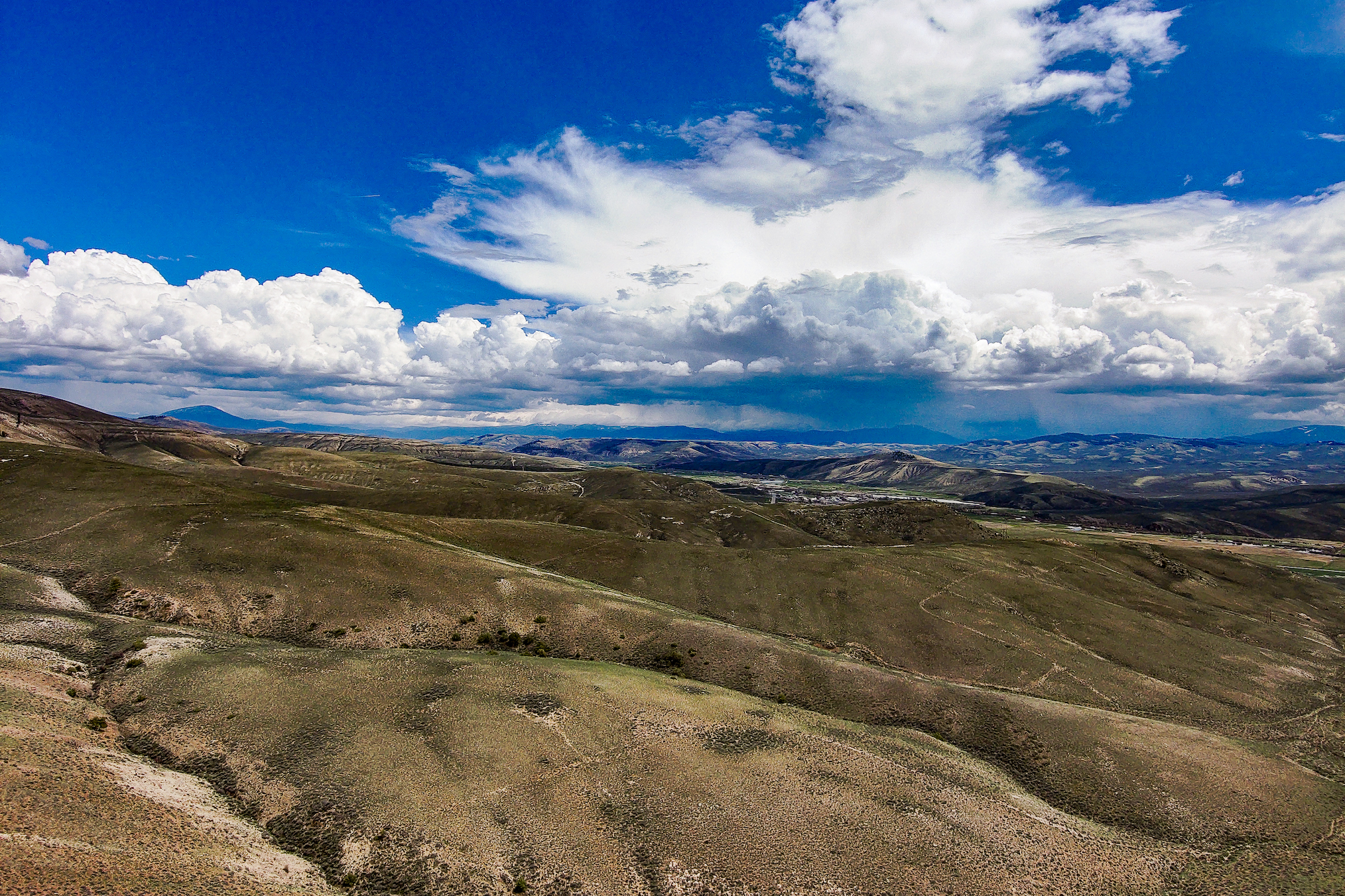 An aerial view of Gunnison, Colorado. There are mountain peaks and sweeping fields.