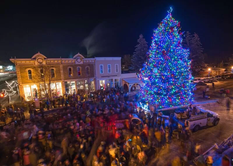 A lit up christmas tree surrounded by a crowd of people.