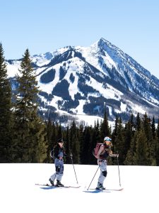 Two women backcountry skiing in Crested Butte on a sunny winter day.