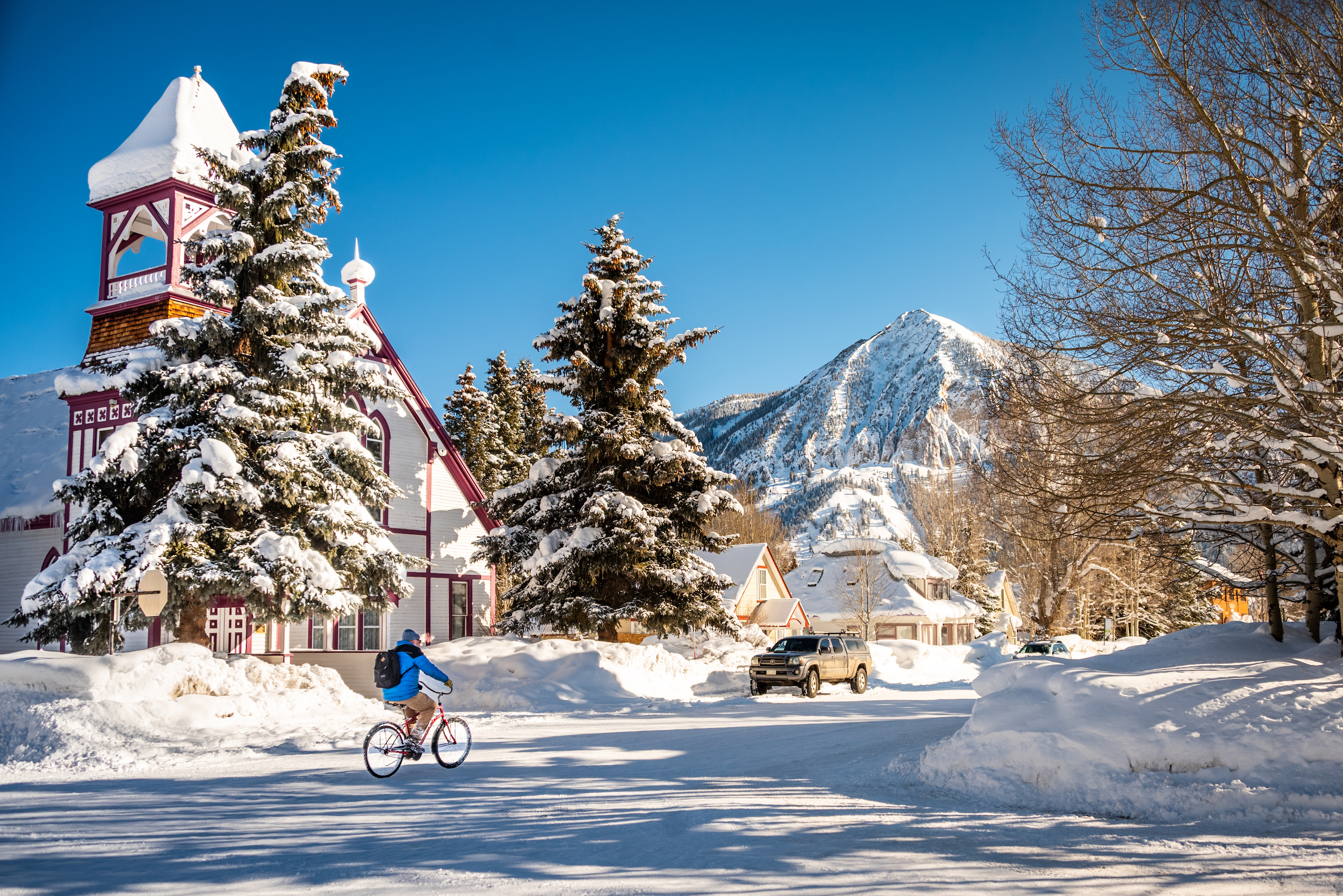 A person rides a bike down a snowy street. Crested Butte in winter is snowy and beautiful