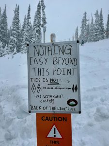 A sign in front of a snowy slope, set up by Crested Butte Ski Patrol.