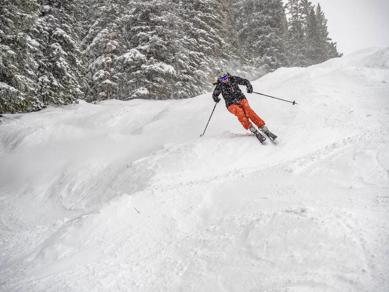 A skier skis down a powder run