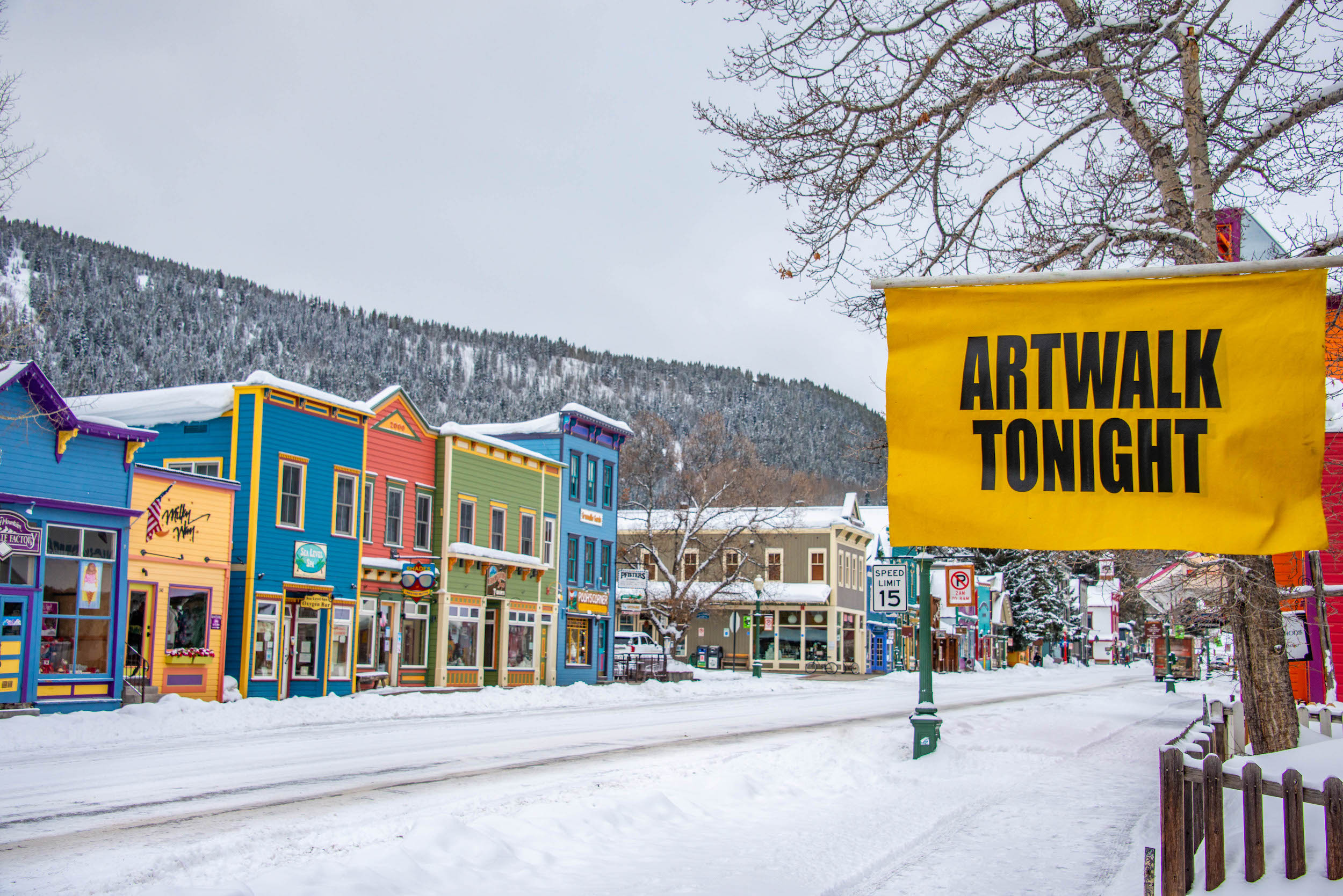 Downtown Crested Butte in the snow with a sign that says "artwalk tonight" advertising the monthly art walk to see local art in Crested Butte