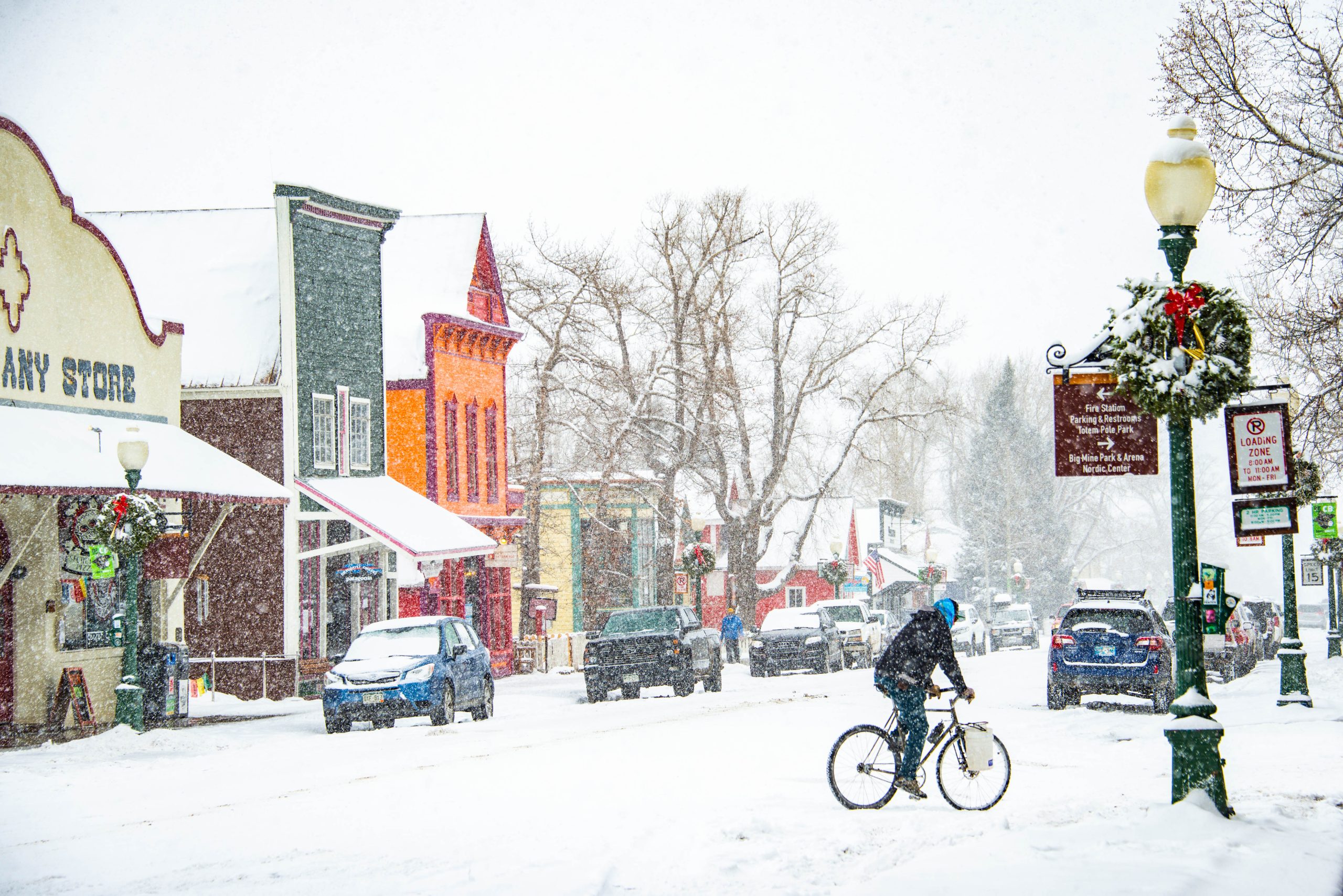 A person on a bike rides on a snowy downtown street