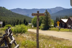 A road sign in downtown Tincup, CO in summer, with mountains in the background.