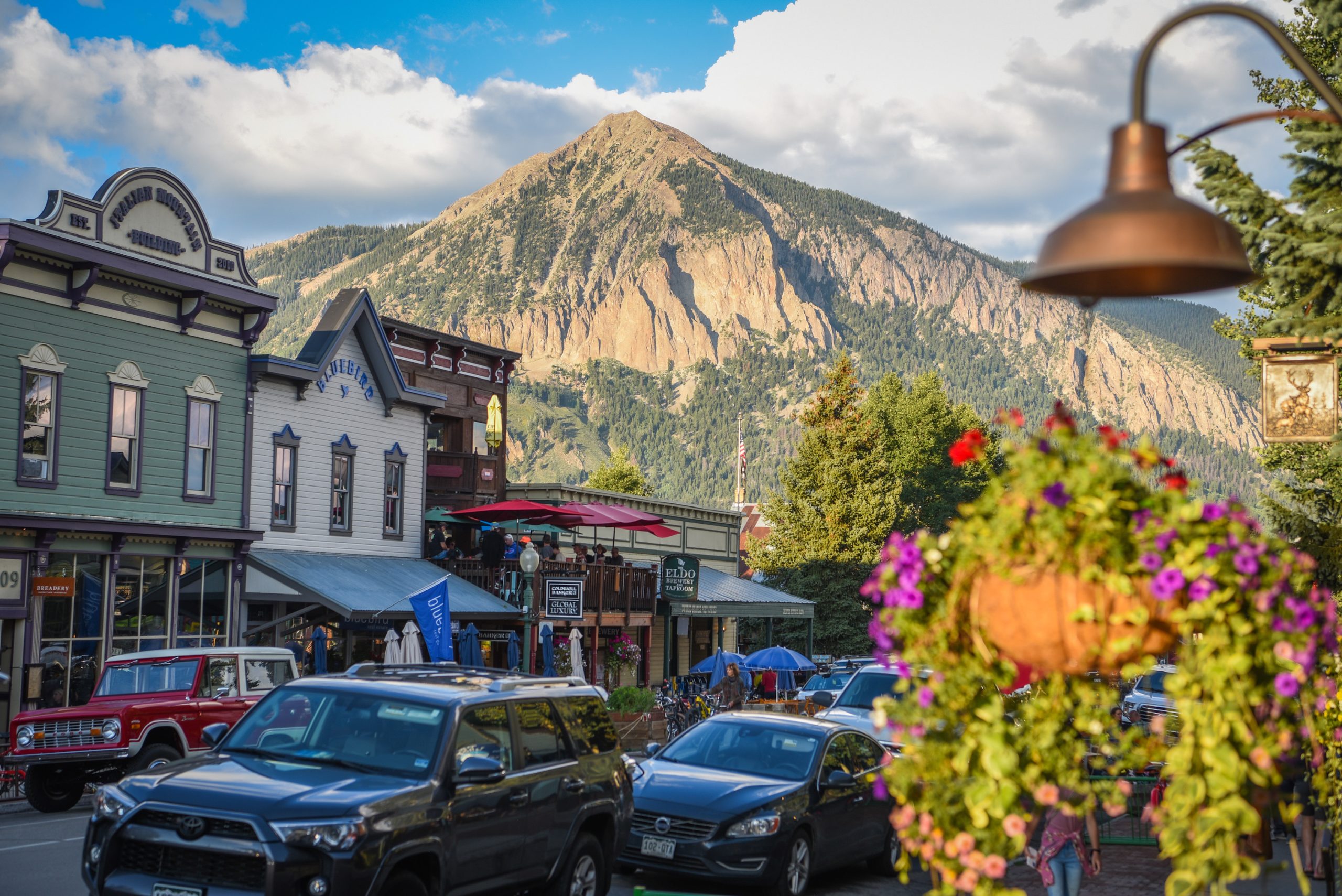 a downtown street with a pointy mountain peak in the background. Elk Avenue is Crested Butte's downtown. Find places to eat and get drinks, shops, galleries and more. 