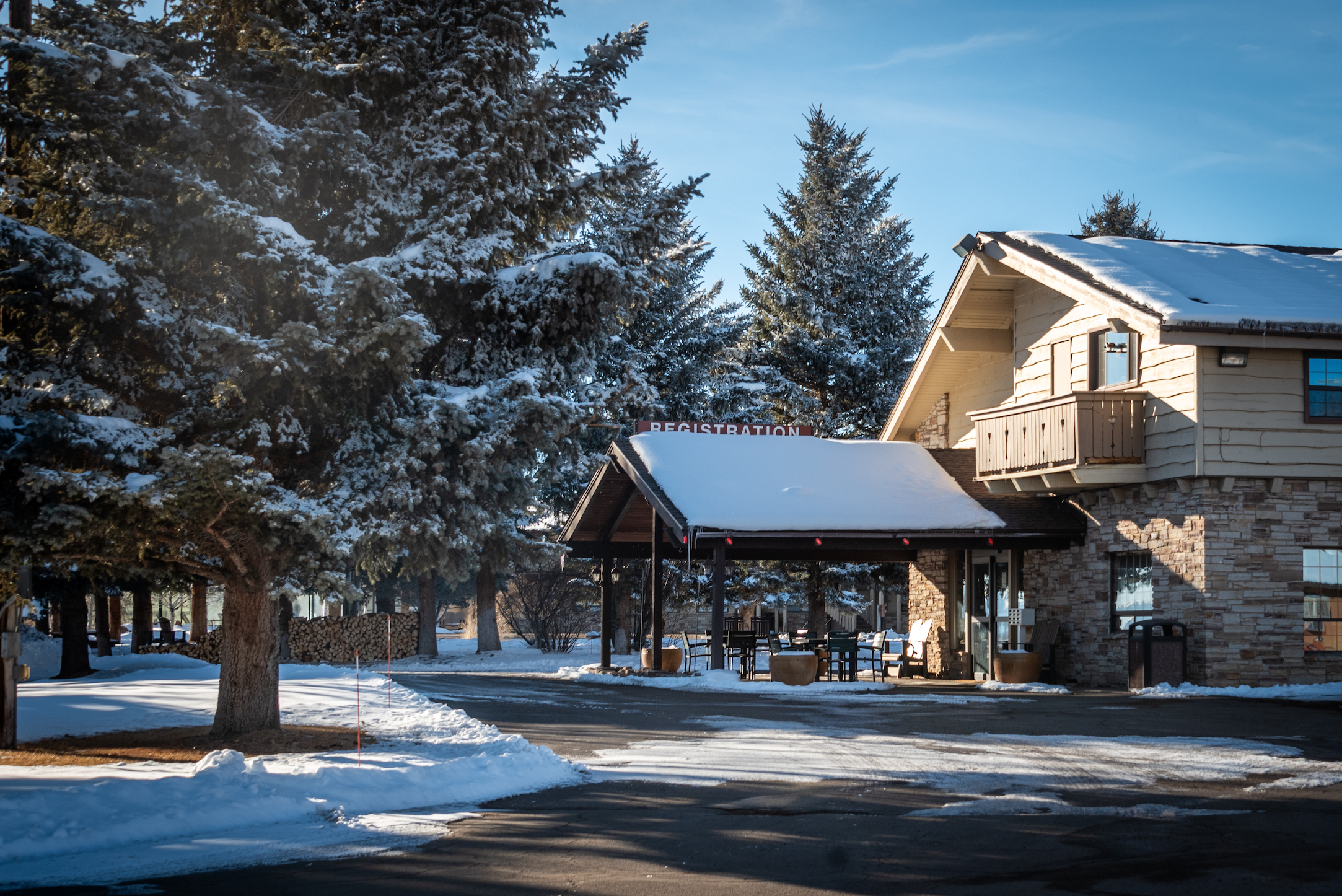A lodge dusted in snow with a big tree in front of it. Gunnison lodging