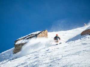 A skier skis down a steep section of the Headwall at Crested Butte on a bluebird day