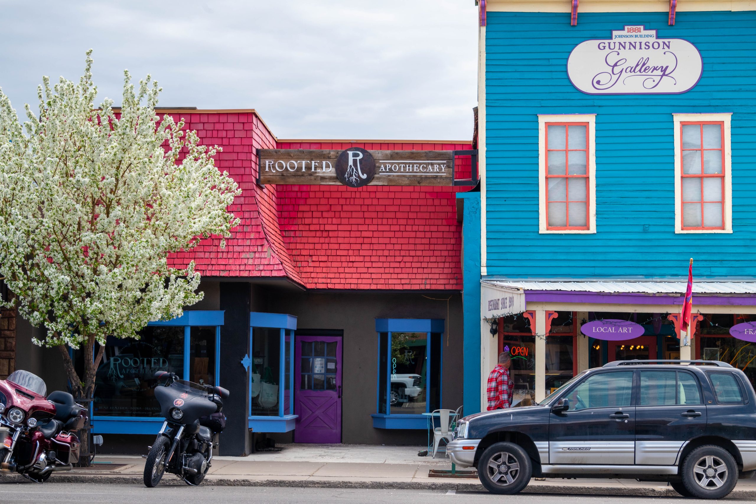 Flowers bloom in front of colorful storefronts in downtown Gunnison, a Colorado vacation travel destination.