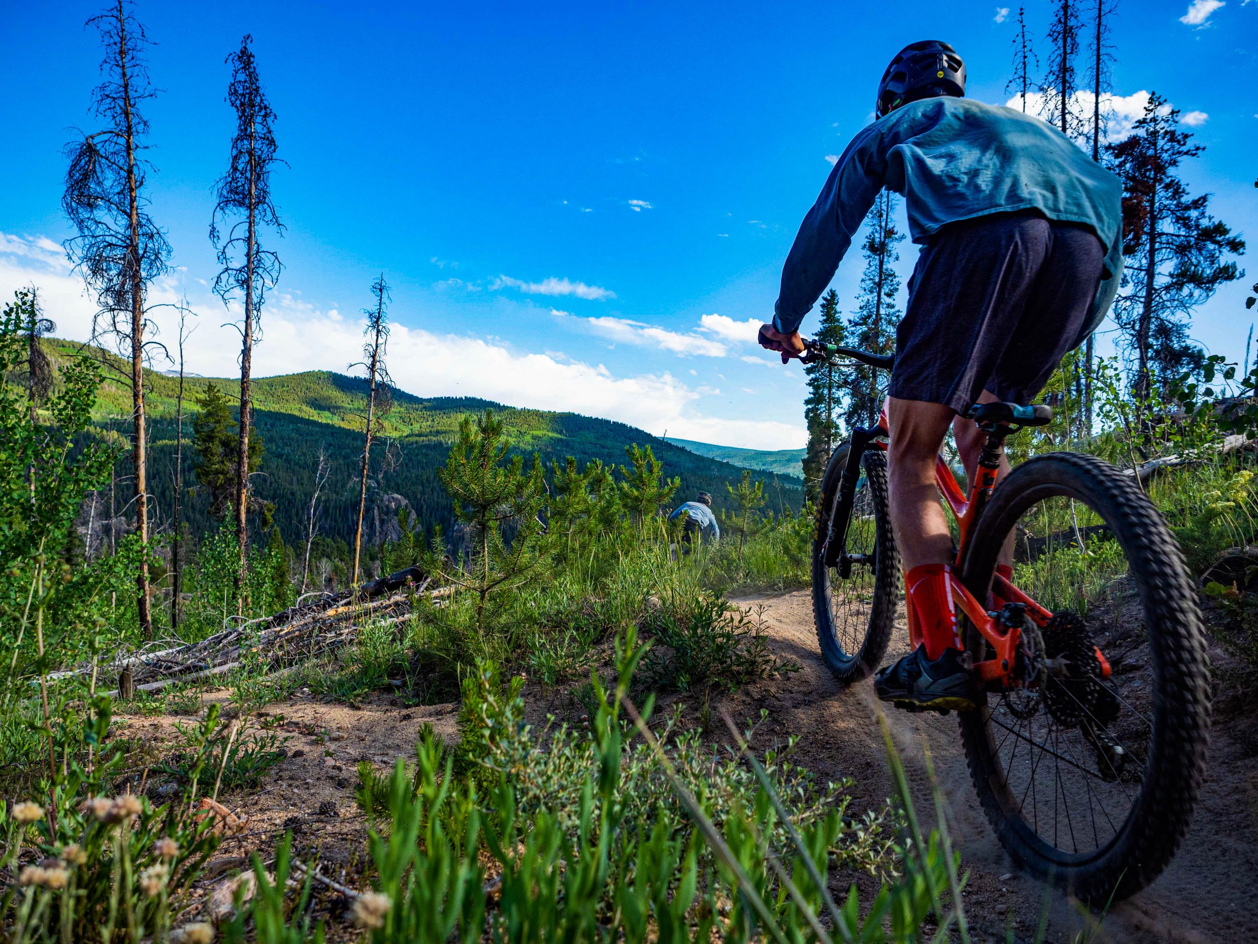 A mountain biker tops out on a ridge overlooking lush green mountains.