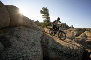 A man mountain bikes over rocks at sunrise at Hartman Rocks in Gunnison, Colorado.