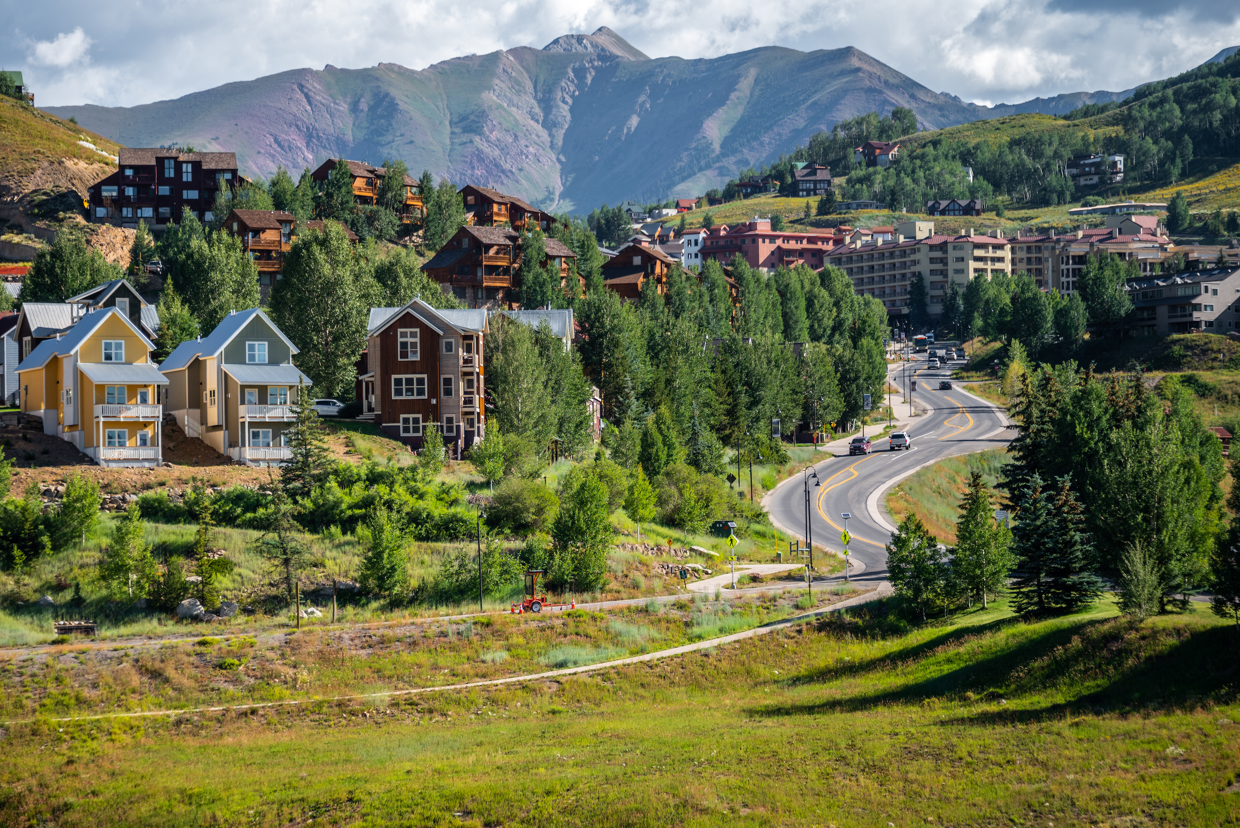 Large vacation rentals on a hillside with a mountain peak in the background. These properties are mt. crested butte lodging