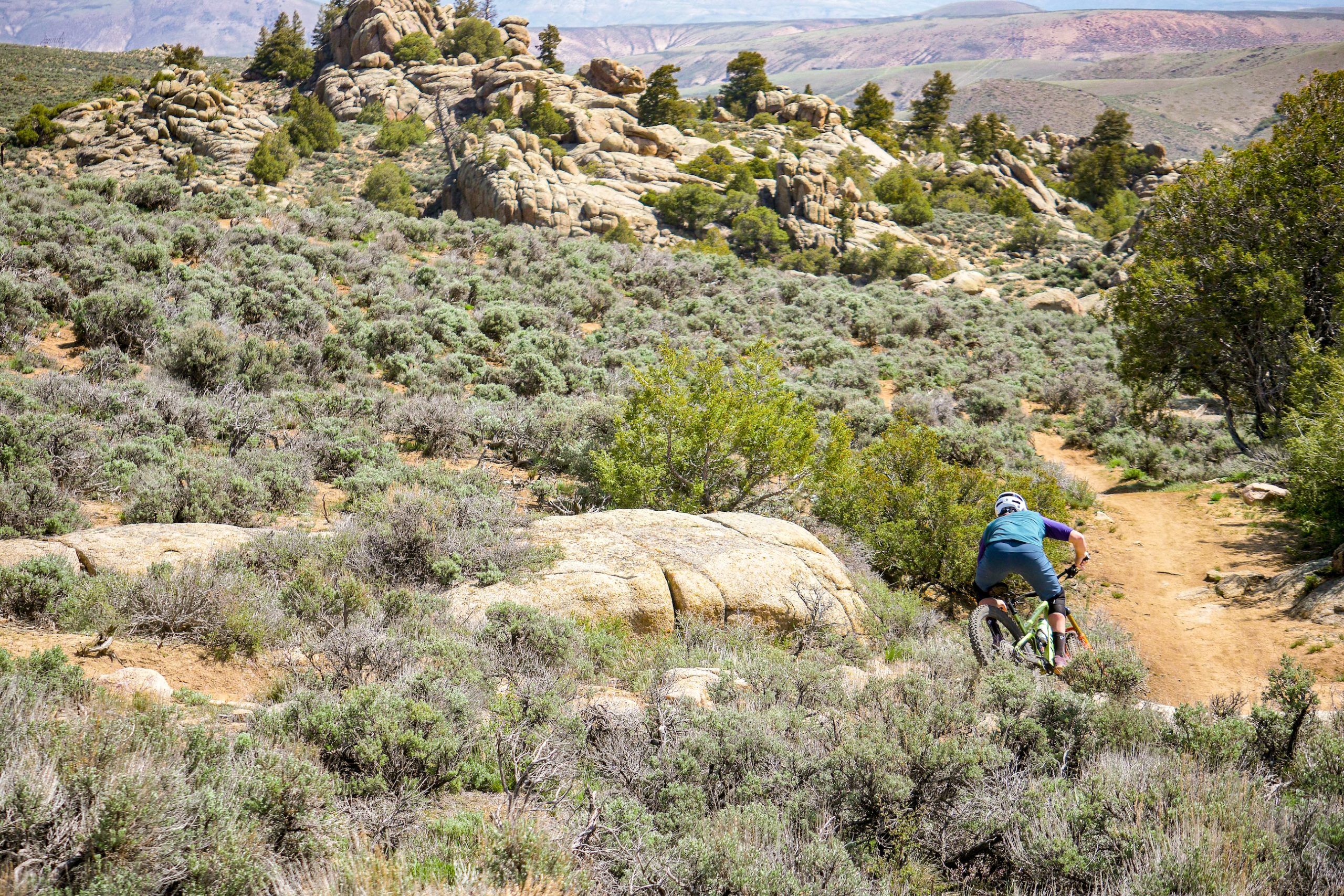 A mountain biker riding in a rocky environment with sage brush