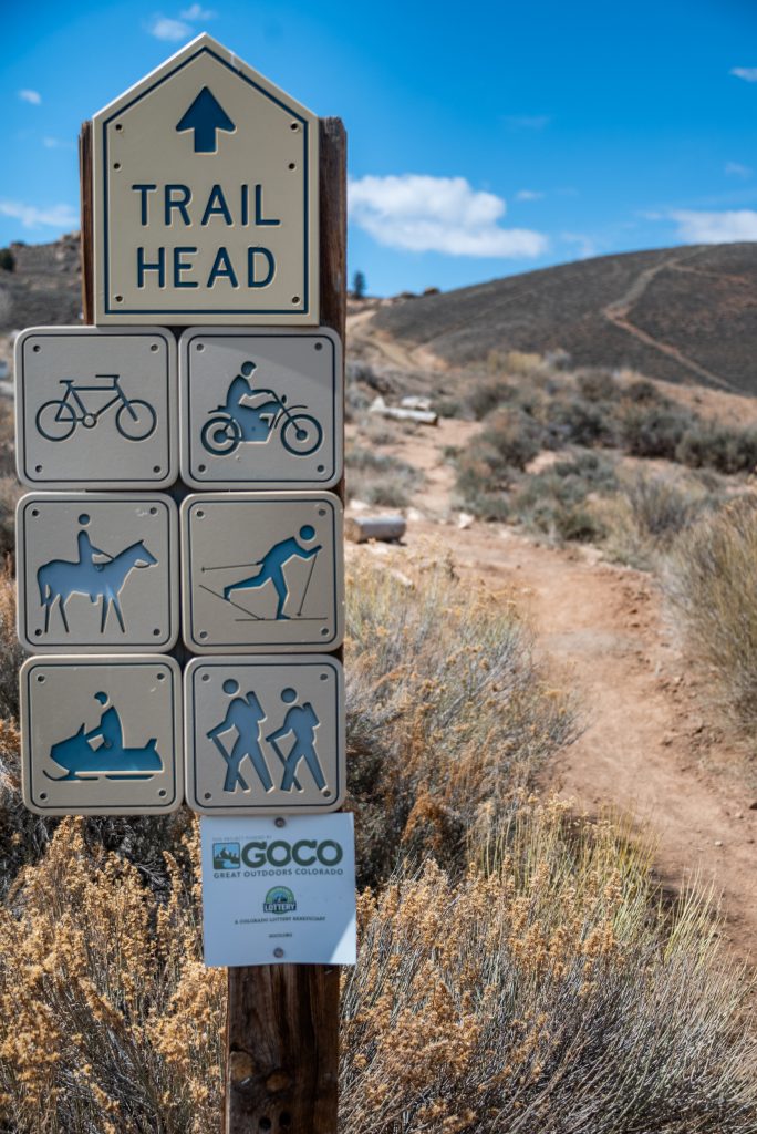 A sign that indicates the different uses for the trails at hartman rocks in gunnison. The signs show the multi-use options of biking, horseback riding, snowmobiling, dirt biking, nordic skiing and hikes