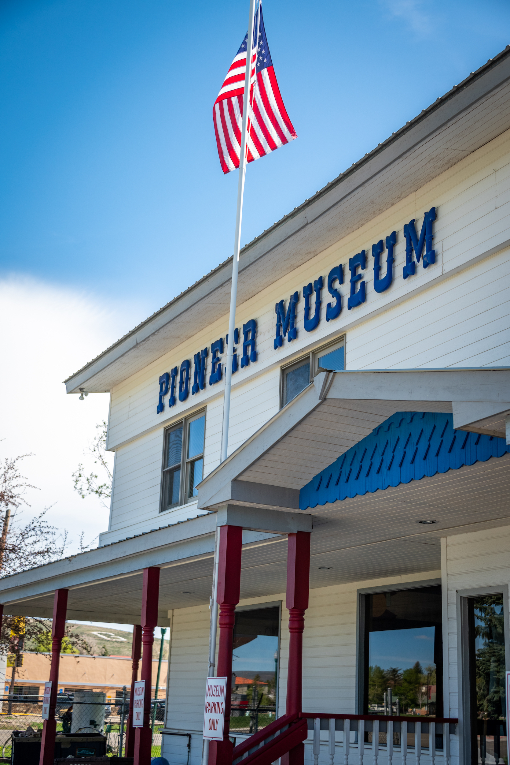 The front of a building with the words "Pioneer Museum" and a flag pole with a red, white, and blue flag.