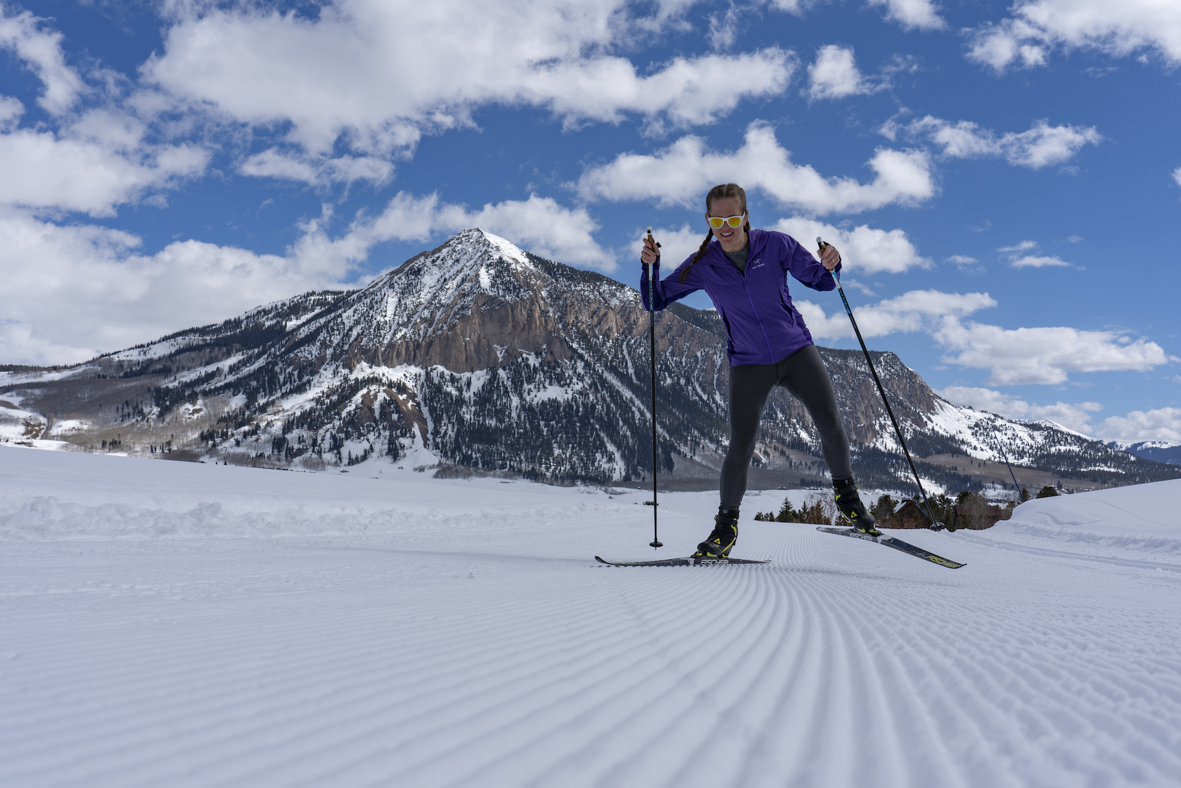 A person skis on skinny skis with a mountain peak in the background. Nordic Skiing Crested Butte