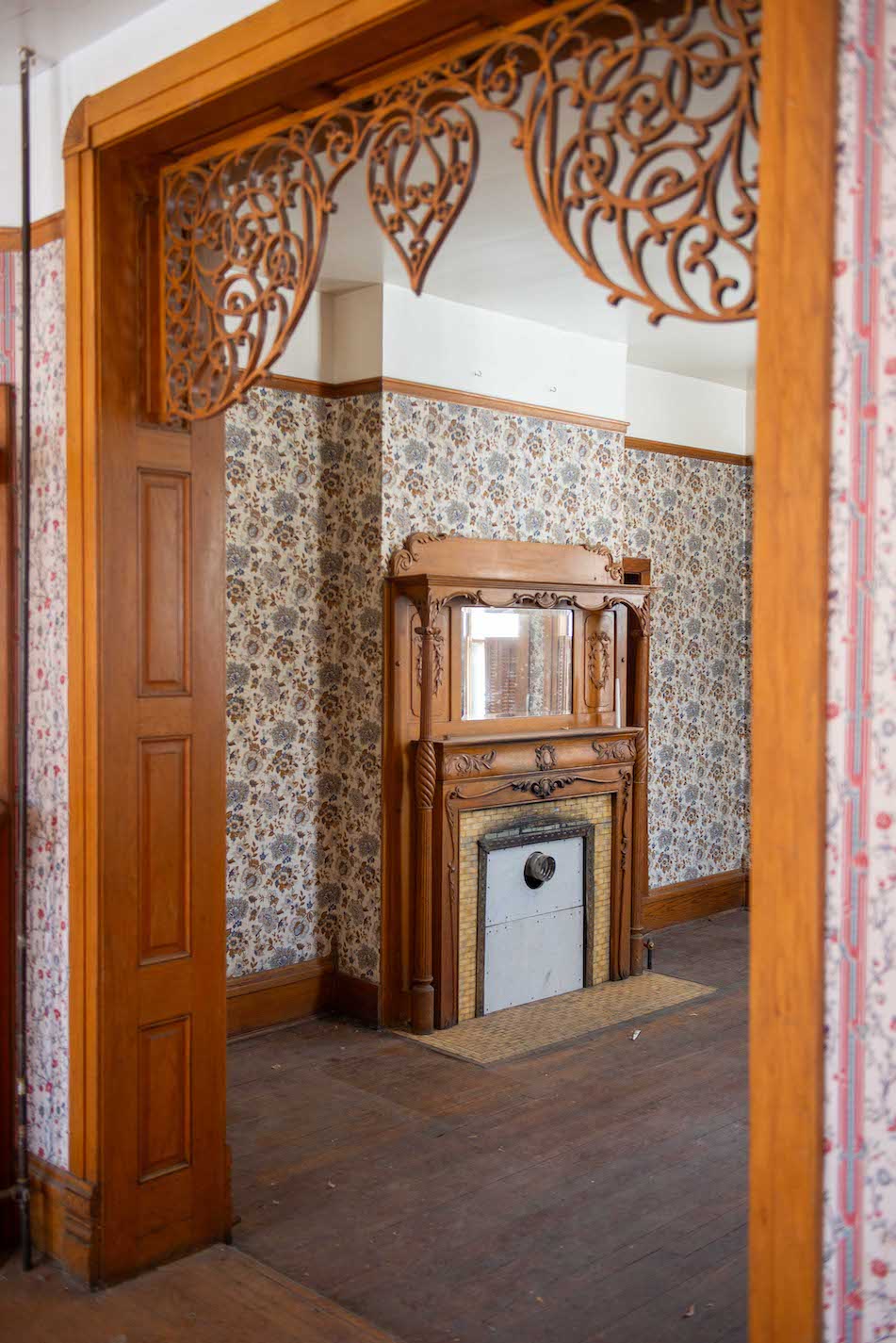 An ornate wooden doorframe framing a room a fireplace is in.