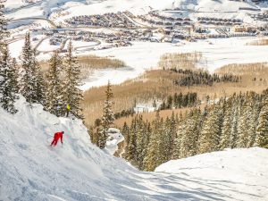 Looking down at a red-jacketed skier skiing Peel at Crested Butte.