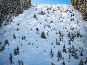 A skier in a red jacket skis down Rambo, a very steep cut run at Crested Butte.