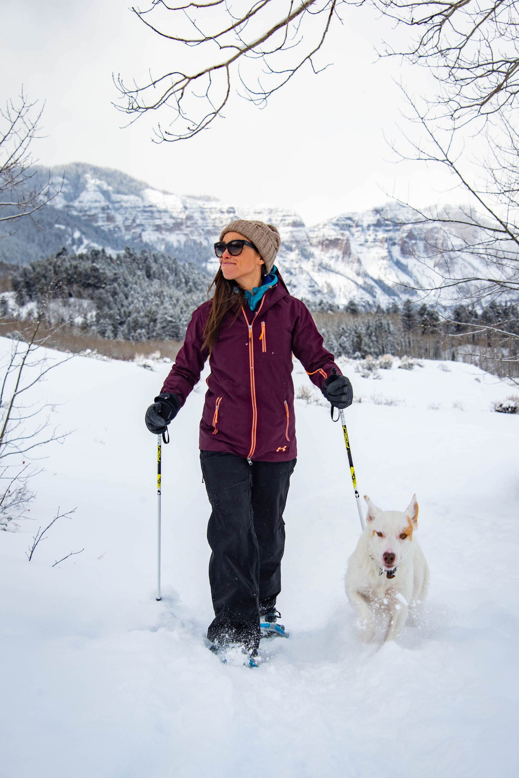A woman walks with a dog on a snowshoe trail. Snowshoeing is a fun way to get outside and enjoy winter in Crested Butte