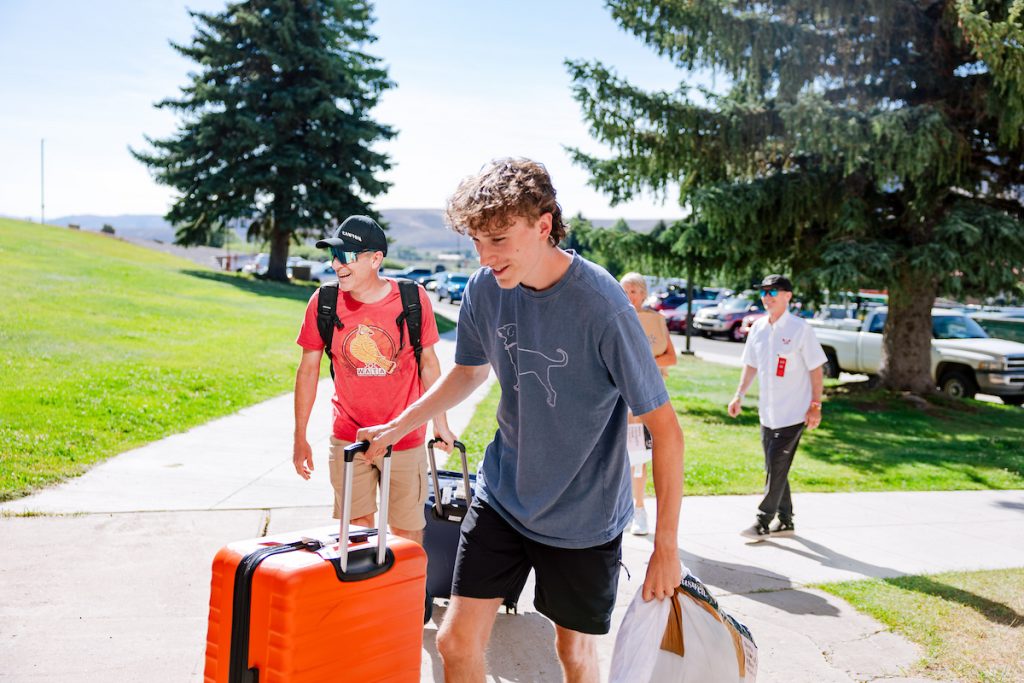western-colorado-university-move-in-day. A student and his dad pull suitcases up a hill as they enter the Escalante Complex.